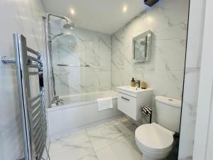 a white bathroom with a toilet and a shower at Deluxe One-Bedroom Apartment, Central in Swindon