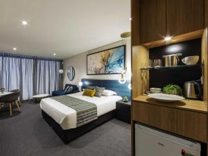 a hotel room with a large bed and a desk at Mercure Canberra Belconnen in Canberra
