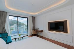 a hotel room with a bed and a flat screen tv at Oyster Bay Vũng Tàu - Seaside Pool Escape in Vung Tau