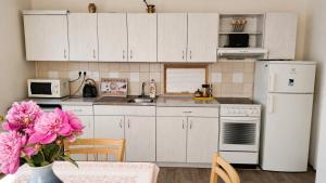 a kitchen with white cabinets and pink flowers in a vase at Retro chalupa Sobkovice in Sobkovice