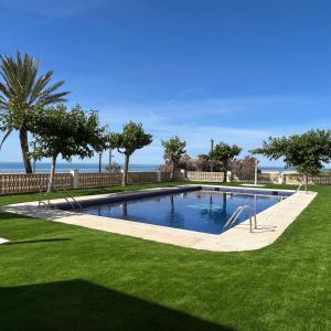 a swimming pool in a yard with grass and trees at Right on the beach in Cubelles +68 photos