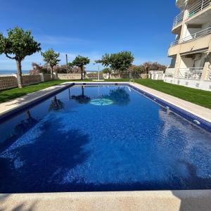 a swimming pool with blue water in front of a building at Right on the beach in Cubelles