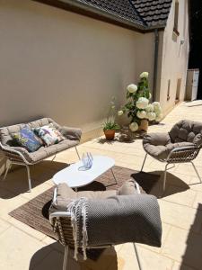 a patio with two couches and a table and chairs at Les Chantereines maison calme au cœur du vignoble champenois in Brugny-Vaudancourt