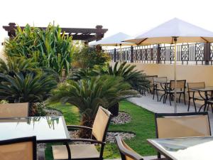 an outdoor patio with tables and chairs and plants at Mövenpick Hotel Apartments Al Mamzar Dubai in Dubai