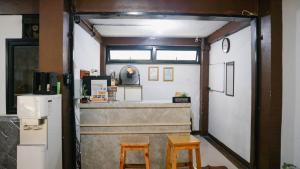 a kitchen with two stools in front of a counter at Artemis Hotel Bekasi in Cikunir Satu