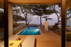 a man standing on a porch looking out at the ocean at The Bay Samui in Choeng Mon Beach