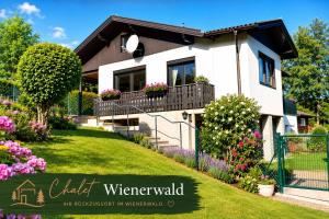 a white house with flowers in the yard at Chalet Wienerwald in Königstetten
