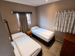 a small room with two beds and a window at Lungile Backpackers in Gqeberha +28 photos