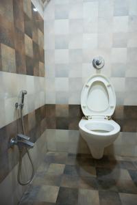 a bathroom with a toilet with a hose at StayGuru Park View Residency in Bhuj +22 photos