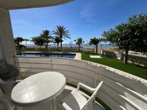 a white table and chairs on a balcony with a view of the beach at Right on the beach in Cubelles