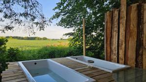 a bath tub sitting on a wooden deck with a field at Benneweis in Brædstrup