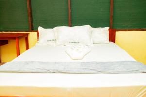 a white bed with white pillows and a green wall at Camp seleu in Dar es Salaam