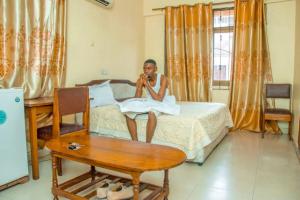 a woman sitting on a bed talking on a cell phone at Camp seleu in Dar es Salaam