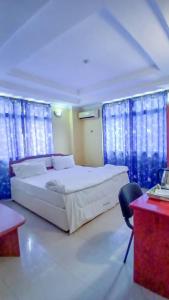 a bedroom with a white bed and blue curtains at Camp seleu in Dar es Salaam