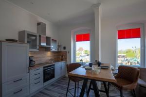 a kitchen with a table and a kitchen with red windows at Heimathafen über dem Hafen - Pub in Pellworm
