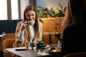 a woman sitting at a table holding a cup of coffee at Palatinus Boutique Hotel in Pécs