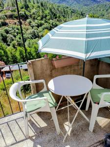 a table and two chairs and an umbrella on a balcony at JOLI 2 PIECES SERRIERA in Serriera