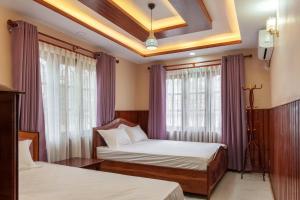 two beds in a room with purple curtains at Comfort Apartment in Bālāju