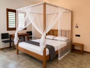 a bedroom with a canopy bed and a desk at Maison le Rêve in Nosy Be