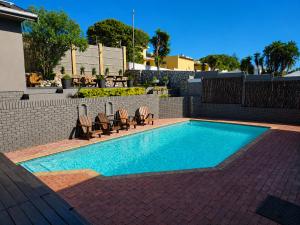 a swimming pool with chairs and a table at Lungile Backpackers in Gqeberha