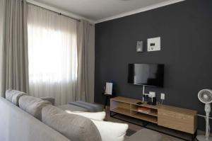 a living room with a couch and a flat screen tv at Tubalala Properties in Rustenburg