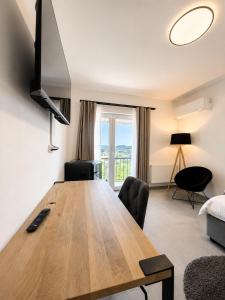 a large wooden table in a living room with a large window at Elion Hotel Siegen in Siegen