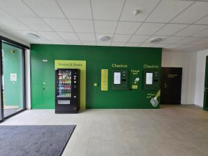 ein Raum mit einer grünen Wand und einem Verkaufsautomaten in der Unterkunft eee Hotel Laakirchen in Laakirchen
