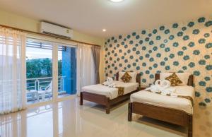 a bedroom with two beds and a balcony at Alisa Krabi Hotel-SHA Plus in Krabi