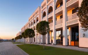 a large white building with trees in front of it at Farovon Khiva Hotel in Khiva