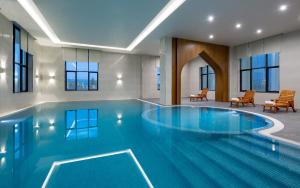 a swimming pool in a hotel with chairs and tables at Farovon Khiva Hotel in Khiva