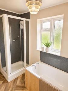 a bathroom with a tub and a shower and a window at The Flat in central Kirkby Stephen in Kirkby Stephen