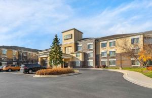 a large building with a car parked in a parking lot at Extended Stay America Select Suites - Chicago - Lombard - Oakbrook in Oakbrook Terrace