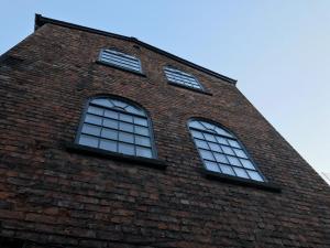 three windows on the side of a brick building at The Eistedfod Penthouse - Berwyn House in Wrexham