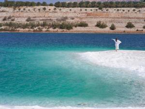 a person standing on a small island in the water at Mövenpick Resort & Spa Dead Sea in Sowayma