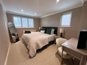 a bedroom with a bed and a desk and two windows at Ivy House in Stockbridge