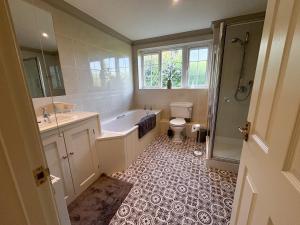 a bathroom with a tub and a toilet and a sink at Ivy House in Stockbridge
