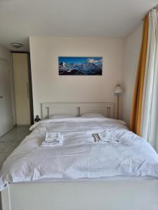 a white bed in a bedroom with snow capped mountains at Alpine Bliss Studio in Wilderswil