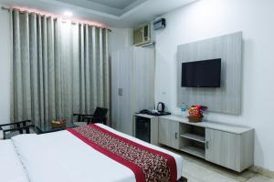 a hotel room with a bed and a flat screen tv at Hotel Ornate Residency And Suites in Gurgaon