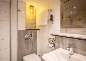 a bathroom with a sink and a toilet and a mirror at Hotel Oscar in Amsterdam