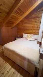 a bedroom with a bed in a wooden cabin at Mountain Attic Near Përmet in Biovizhdë
