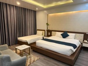 a hotel room with two beds and a couch at Sen Hotel My Dinh Song Da 미딩 in Hanoi