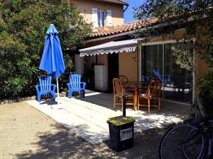 a patio with a table and chairs and a blue umbrella at les lauriers in Saint-Sernin