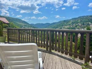 a white chair on a deck with a view of mountains at Hôtel Restaurant & Bien-être Le Chalet des Roches in La Bresse