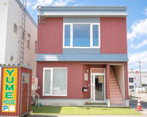 a red house with a sign in front of it at Yume House in Furano