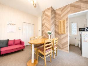 a dining room with a table and a red couch at Yume House in Furano