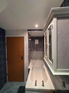 a bath tub in a bathroom with a window and a door at Cosy 2 Story Home Leicester City Centre in Leicester