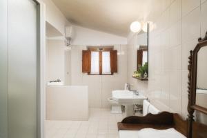 a white bathroom with a sink and a toilet at Castello di Albola in Radda in Chianti +40 photos