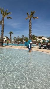 a person with an umbrella standing in the water at a resort at Mobil Home SIBLU VALRAS PLAGE in Sérignan