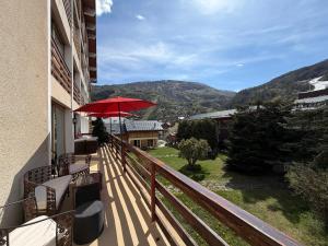 a balcony with a red umbrella and tables and chairs at Mimi lodge familly in Valloire