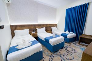 a hotel room with two beds and blue curtains at فندق عصفور 03 in Mecca +89 photos